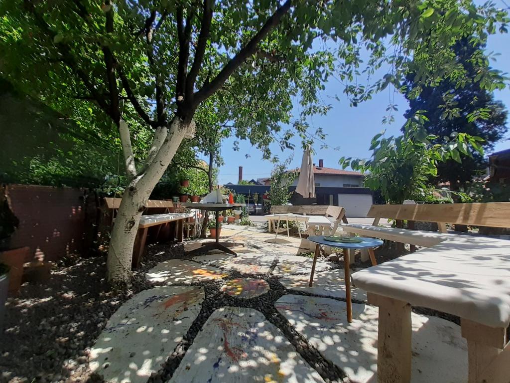 a patio with benches and a tree in a yard at Rooms & Apartment GH Pasha in Tuzla