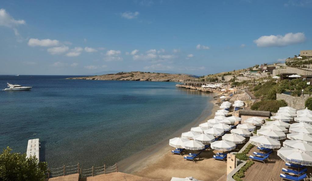 uma praia com guarda-sóis e um barco na água em METT Hotel & Beach Resort Bodrum em Bodrum City