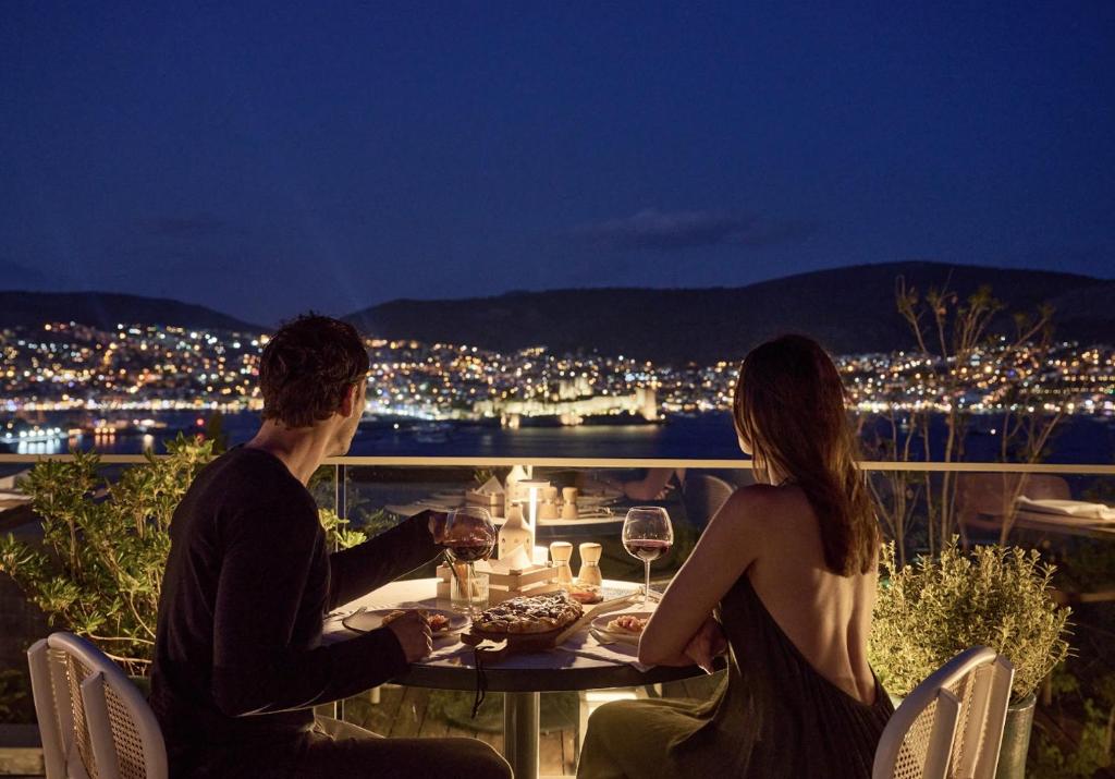 a man and woman sitting at a table with wine glasses at METT Hotel & Beach Resort Bodrum in Bodrum City