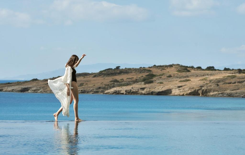 a woman walking on a beach in the water at METT Hotel & Beach Resort Bodrum in Bodrum City