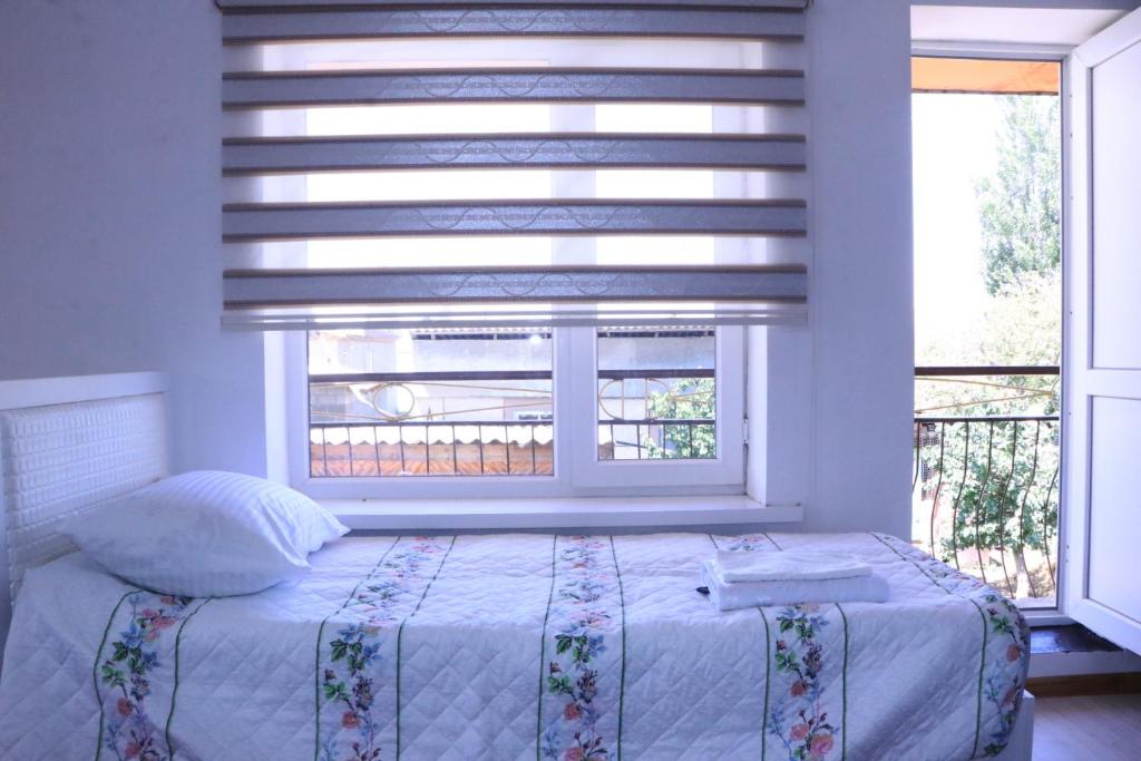 a bedroom with a bed and two windows at Guest House Akbermet in Bokonbayevo