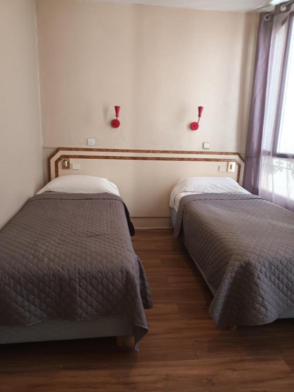 two beds sitting next to each other in a bedroom at Hôtel de Lorraine in Paris