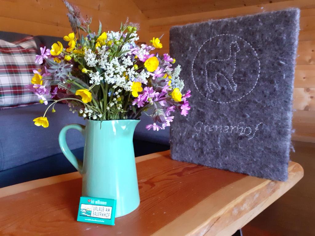 wazon kwiatów na stole obok tablicy w obiekcie Grenerhof w mieście Hopfgarten in Defereggen
