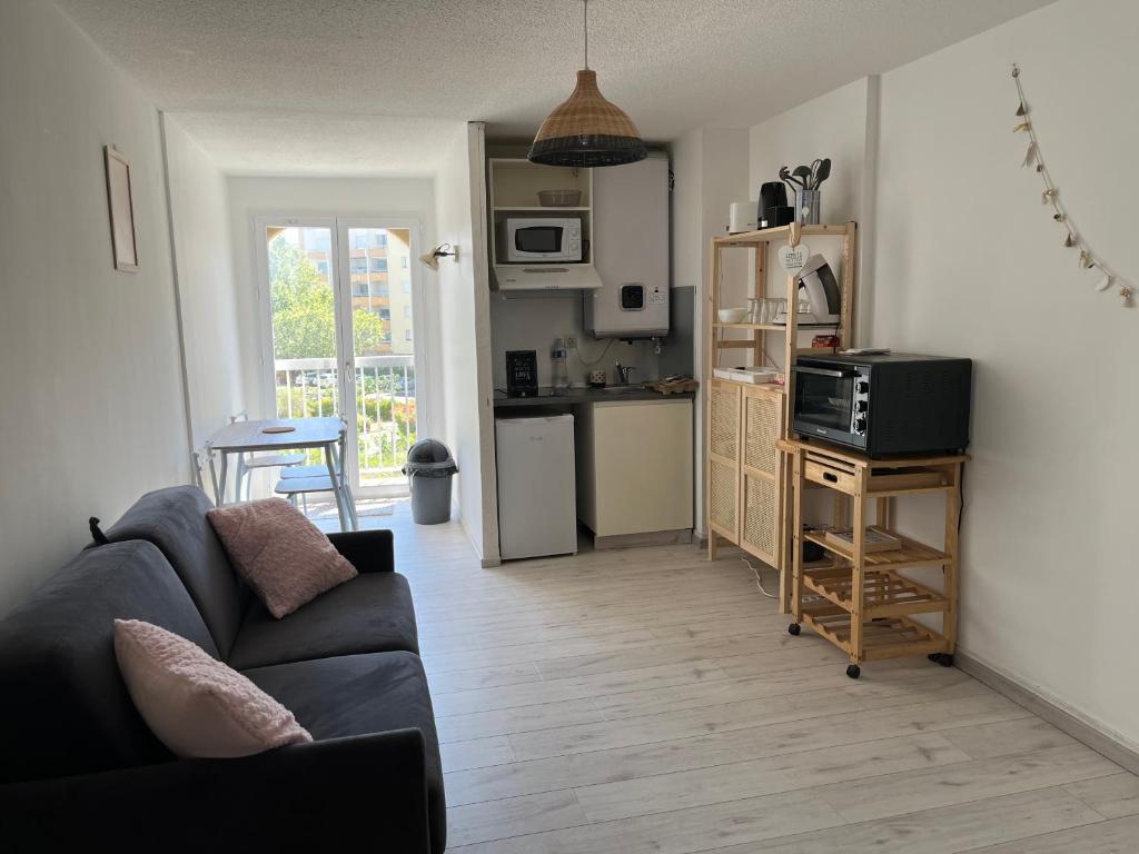 un salon avec un canapé et une cuisine dans l'établissement Logement entier port et plages Carnon, à Carnon-Plage