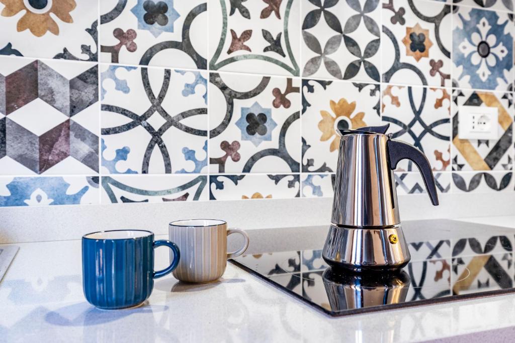 two mugs and a tea kettle on a counter with tiles at Querini Suite-Balcony on canal, close to San Marco in Venice