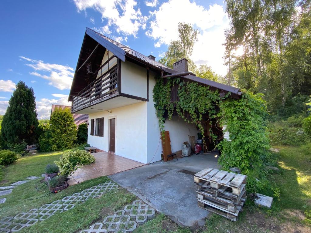 Cette petite maison blanche dispose d'une terrasse en bois. dans l'établissement Kaszuby Dom Letniskowy -u Remika- Holiday Home Sulęczyno, à Å»akowo