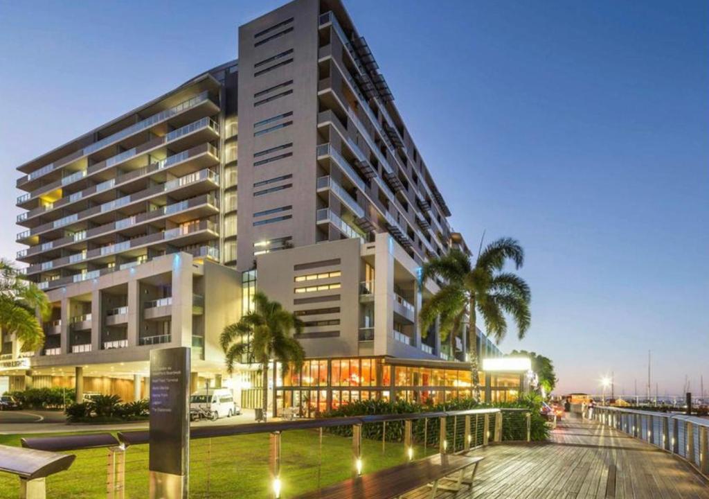 a large building with palm trees in front of it at Lovely One Bedroom Apartment "Cairns Harbour Lights" in Cairns