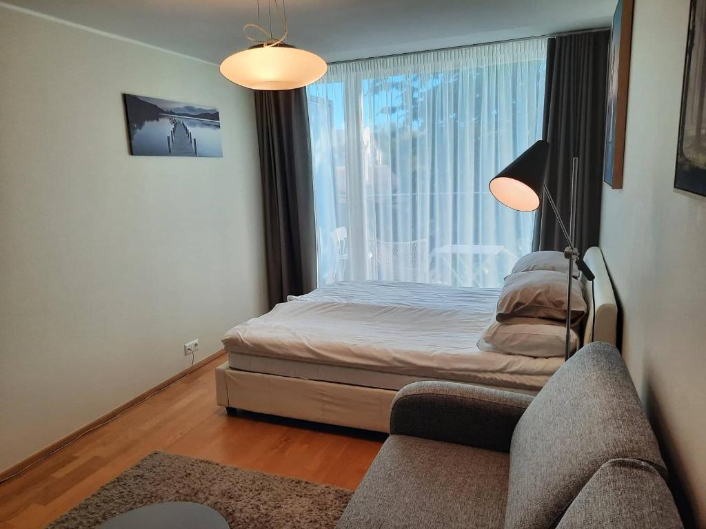 a bedroom with a bed and a window with a couch at Kena, rõduga külaliskorter Aisa 39 in Pärnu