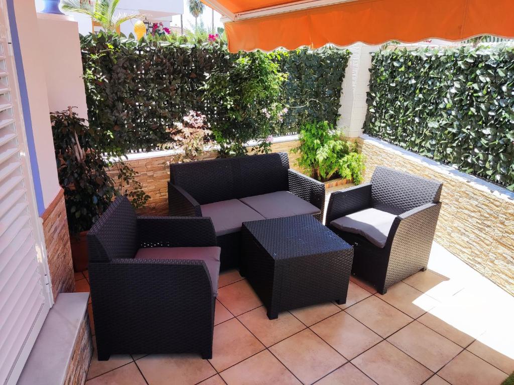een patio met rieten stoelen en tafels in een gebouw bij Alojamiento Los Corrales in Chipiona