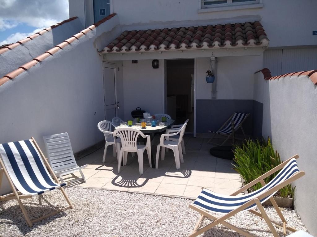 d'un patio avec des chaises et une table. dans l'établissement Maison agréable proche plage et bourg, 6 couchages, terrasse et équipements complets, La Guérinière - FR-1-224B-42, à La Guérinière