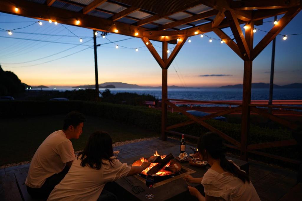 a group of people sitting around a table with a fire at Seaside Villa KAMANO in Aji