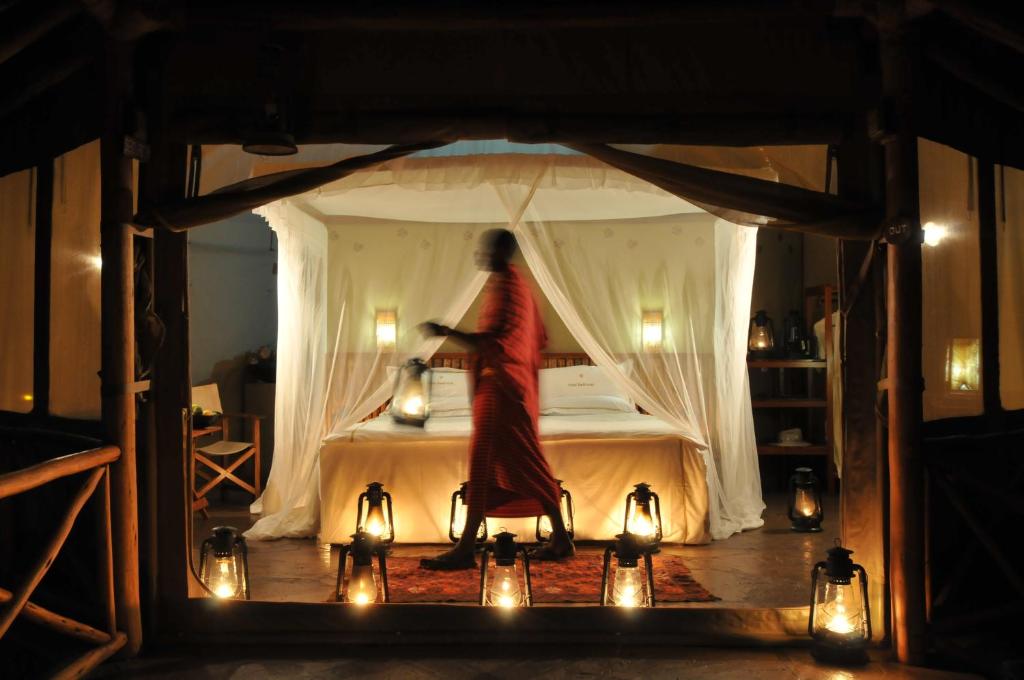 una donna che si trova su un letto in una stanza con luci di Severin Safari Camp a Tsavo West National Park