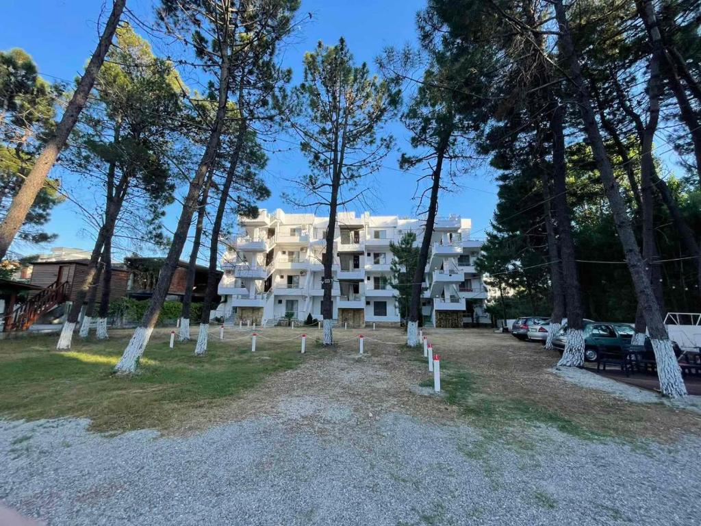 un gran edificio blanco con árboles delante de él en Aparthotel Vila Tufi, en Velipojë