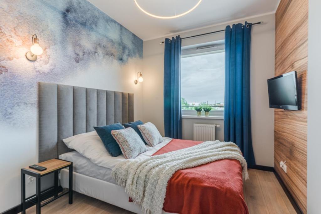 Schlafzimmer mit einem Bett mit blauen Vorhängen und einem Fenster in der Unterkunft Sapphire Premium Apartment in Graudenz