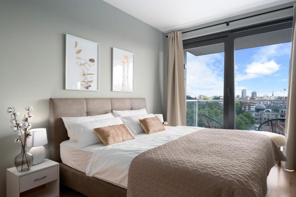 a bedroom with a large bed and a large window at SHS HOMES-LUXE HIGHRISE, 2 BEDROOMS, KITCHEN, FREE PARKING, STUNNING VIEW, LARGE TARRASSE, Workspace in Hasselt