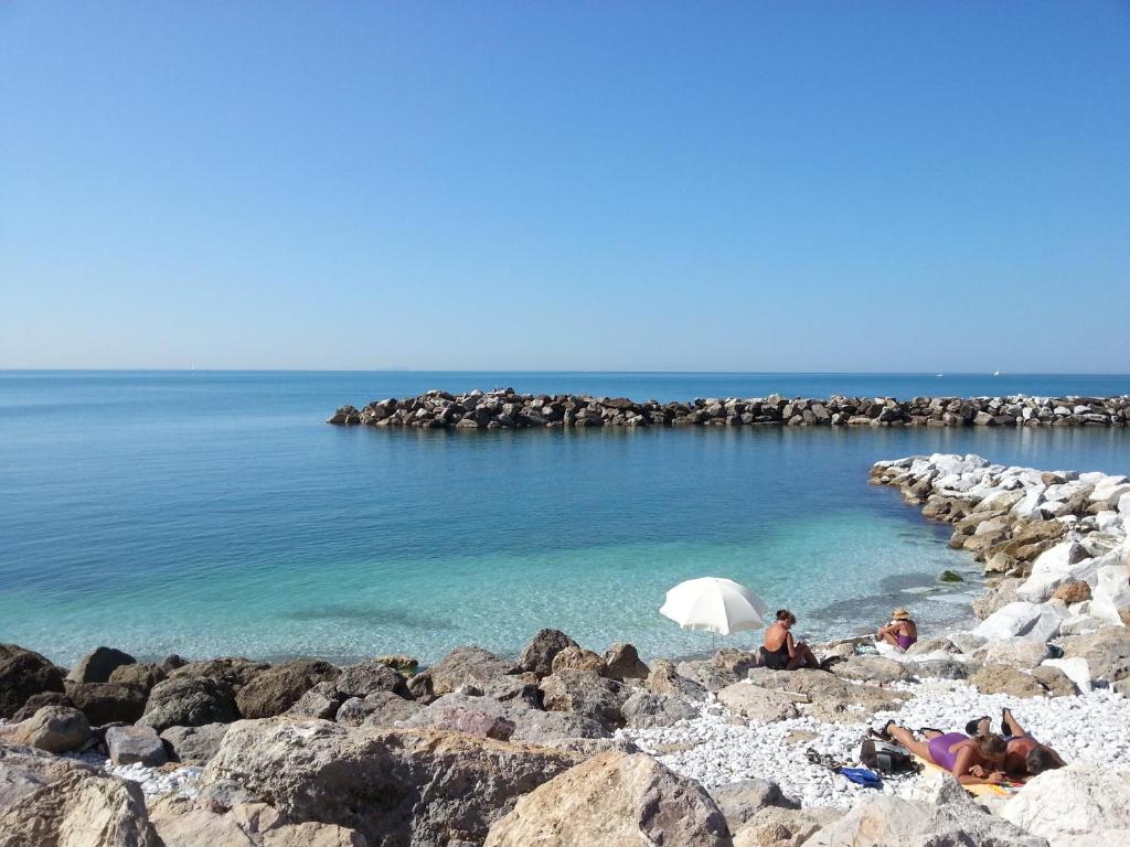 a group of people sitting on a beach with an umbrella at Villino Ermione in Marina di Pisa