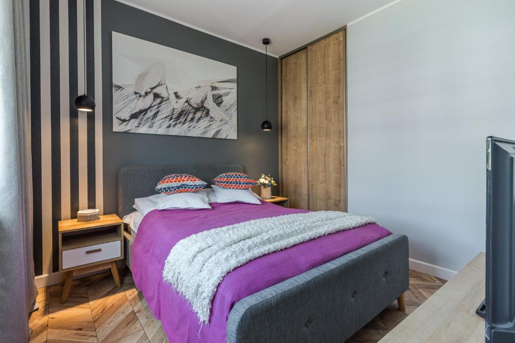 sypialnia z dużym łóżkiem i fioletowym kocem w obiekcie Lead Apartment w Grudziądzu