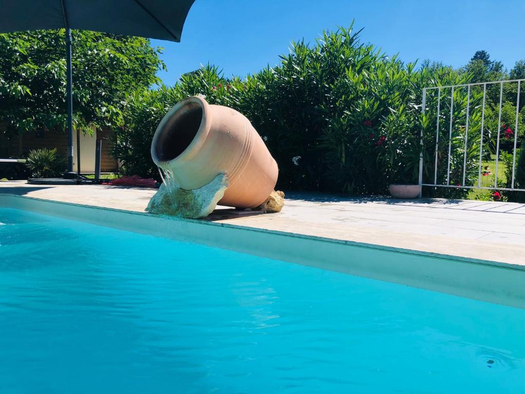 een grote pot aan de zijkant van een zwembad bij Villa piscine privée vallée châteaux Dordogne in Saint-Cybranet