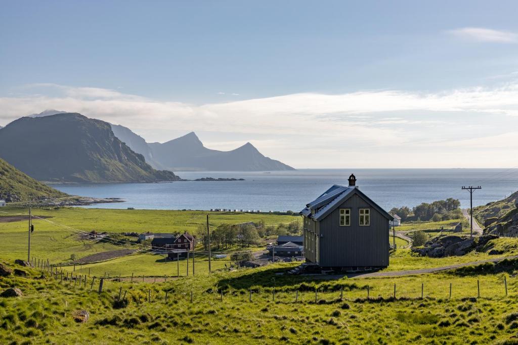 a man standing on top of a small house in a field at Feriehus med flott havutsikt ved Hauklandstranden in Leknes