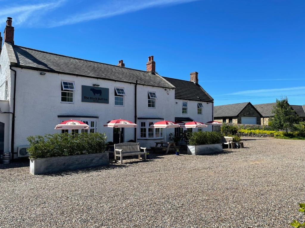 a white building with red umbrellas in front of it at The Black Bull Inn in Lowick