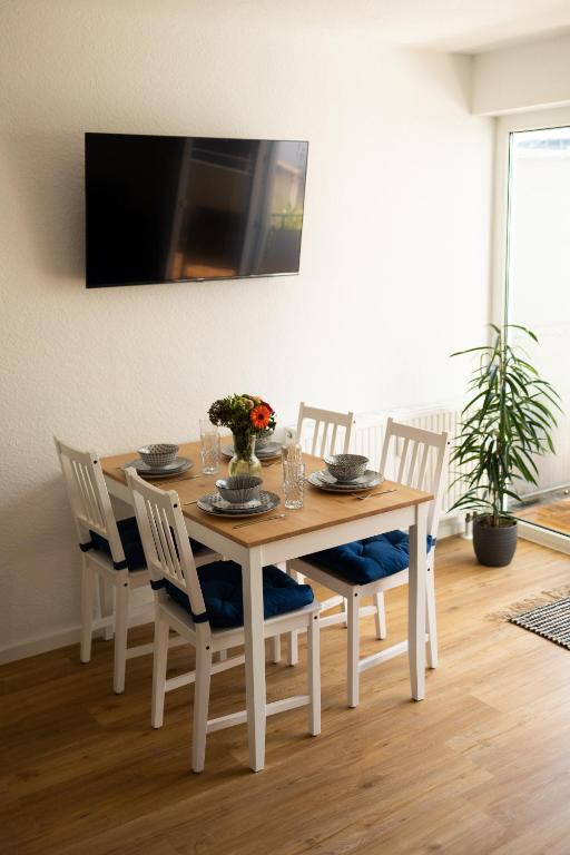 a dining room table with chairs and a tv on the wall at Casa d‘Oro in Friedrichshafen