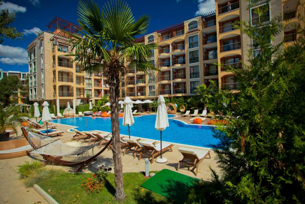 a resort swimming pool with a hammock and a palm tree at Harmony Suites 2,3 in Sunny Beach