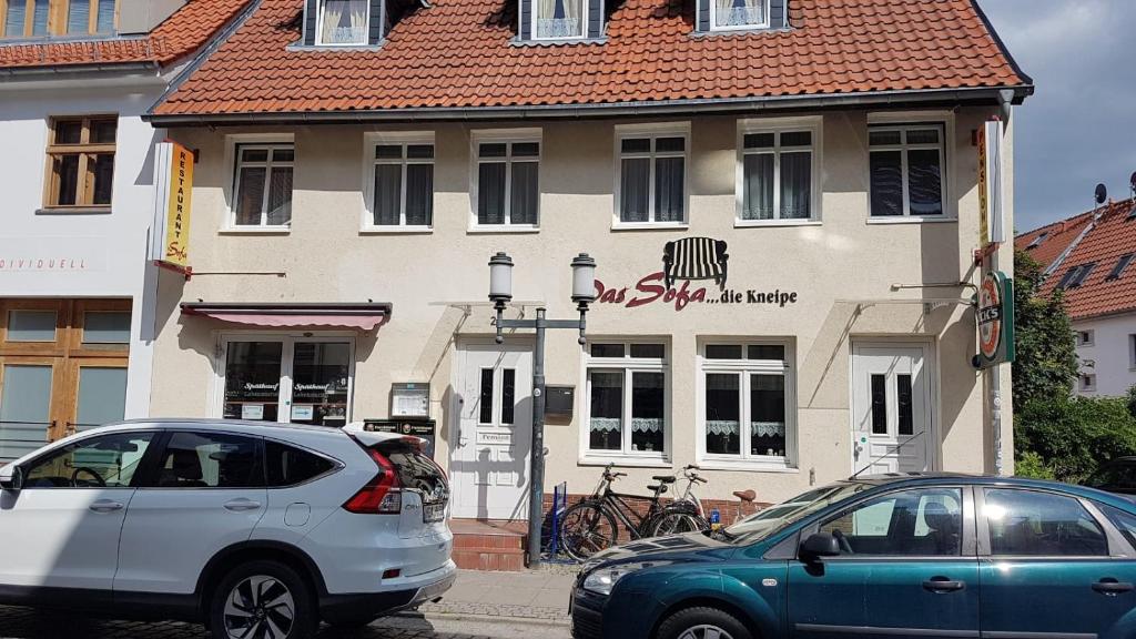 zwei Autos vor einem Gebäude geparkt in der Unterkunft Das Sofa Restaurant-Hotel-Spätkauf in Greifswald