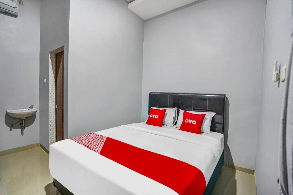 1 dormitorio con 1 cama grande con almohadas rojas en OYO 91181 Beda Arga Residence, en Medan