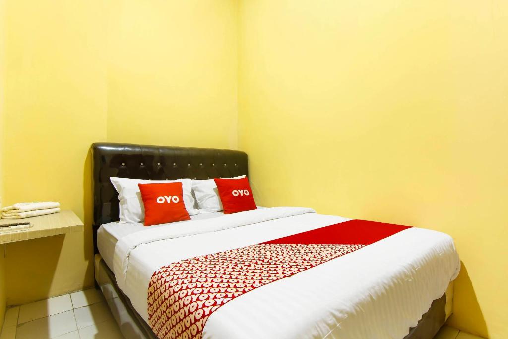 ein Schlafzimmer mit einem Bett mit zwei roten Kissen in der Unterkunft OYO 90900 Pagi Sore Residence in Padang