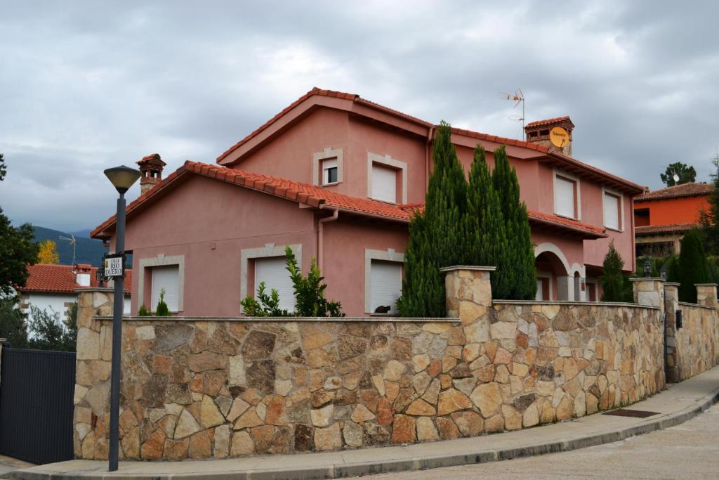 una casa rosa detrás de una pared de piedra en VILLA LAS PALMERAS, en Arenas de San Pedro