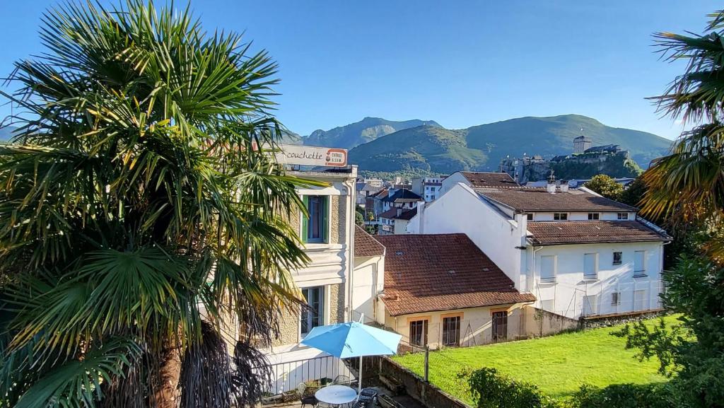 un parasol bleu devant un bâtiment planté de palmiers dans l'établissement Charmant 2 pièces avec terrasse proche centre ville - Parking Gratuit à proximité, à Lourdes