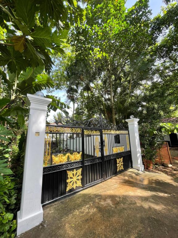 a black fence with a gate and trees at Sunhaven Villa & Apartment in Hikkaduwa
