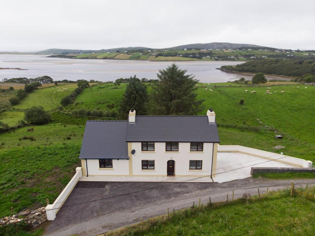 a white house in a field with a body of water at Jack's House in Glenties