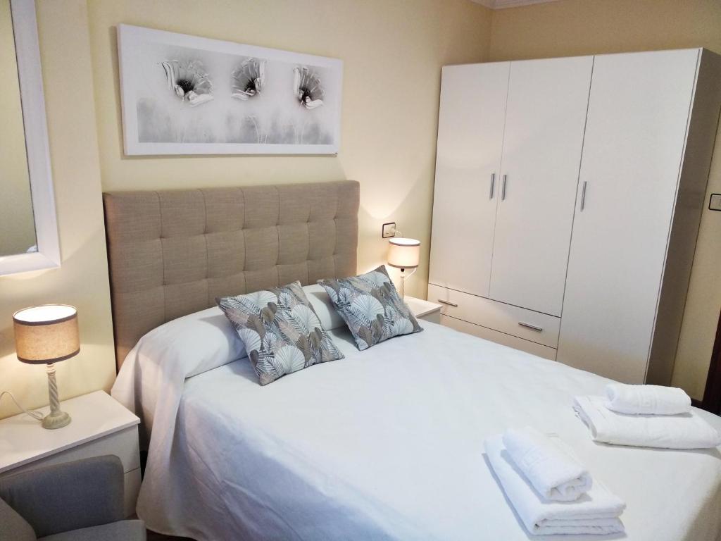 a bedroom with a large white bed with two pillows at O AREAL DE NATALIA in Muxia