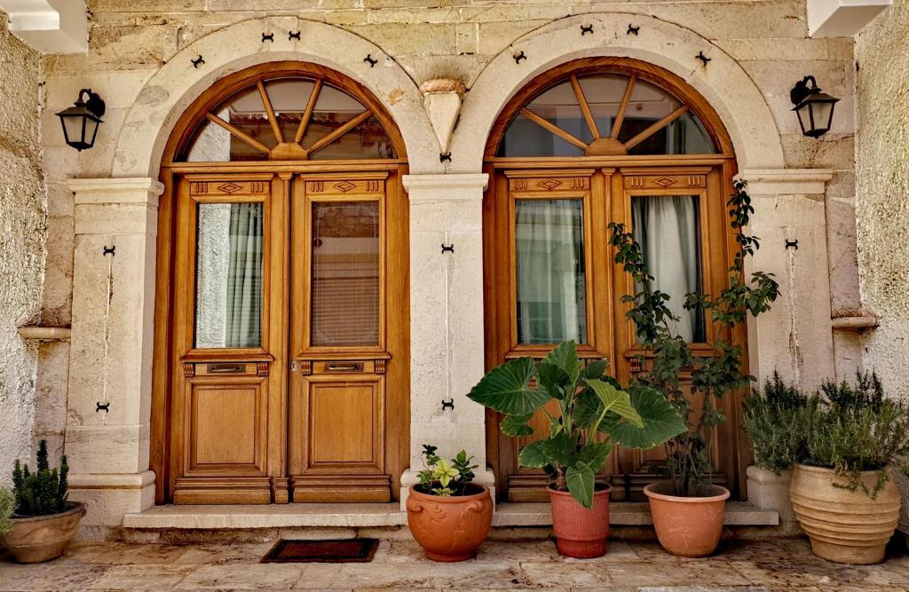 a house with two wooden doors and potted plants at Ξενώνας Μυρτώ in Andritsaina