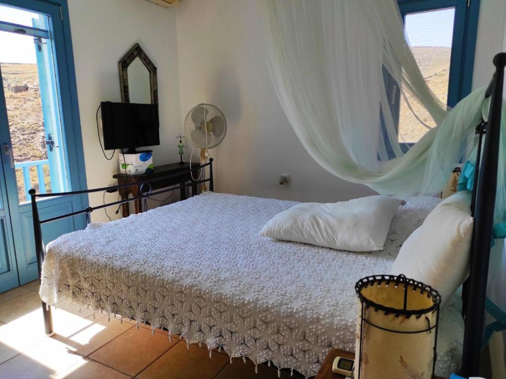 a bedroom with a bed with a mosquito net at Villa Mariza Kythnos in Kithnos