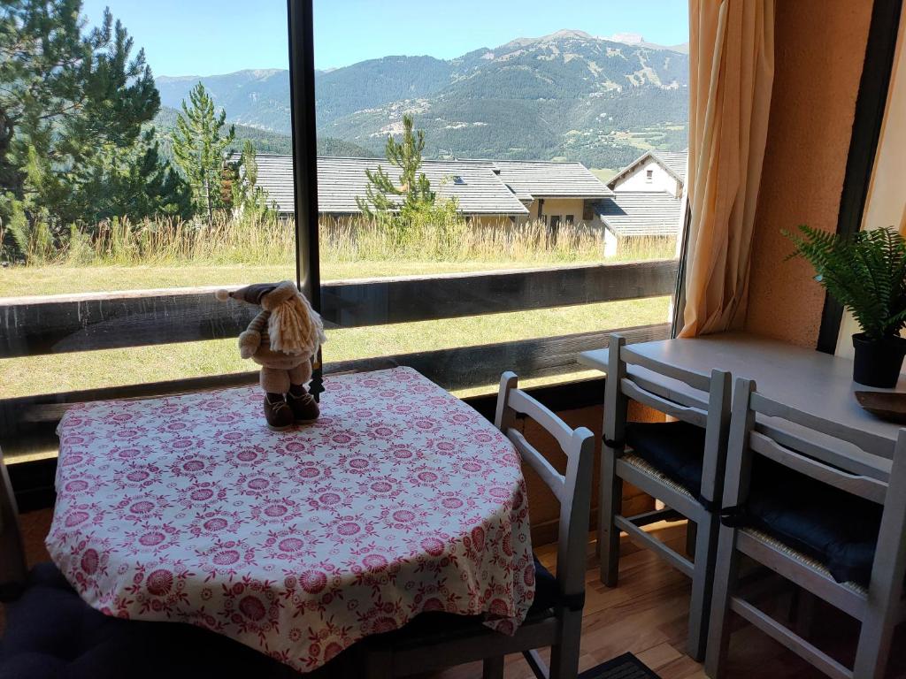 a teddy bear sitting on a table in front of a window at Petit cocon plein sud vue montagnes Lesclesdenicole in Barcelonnette