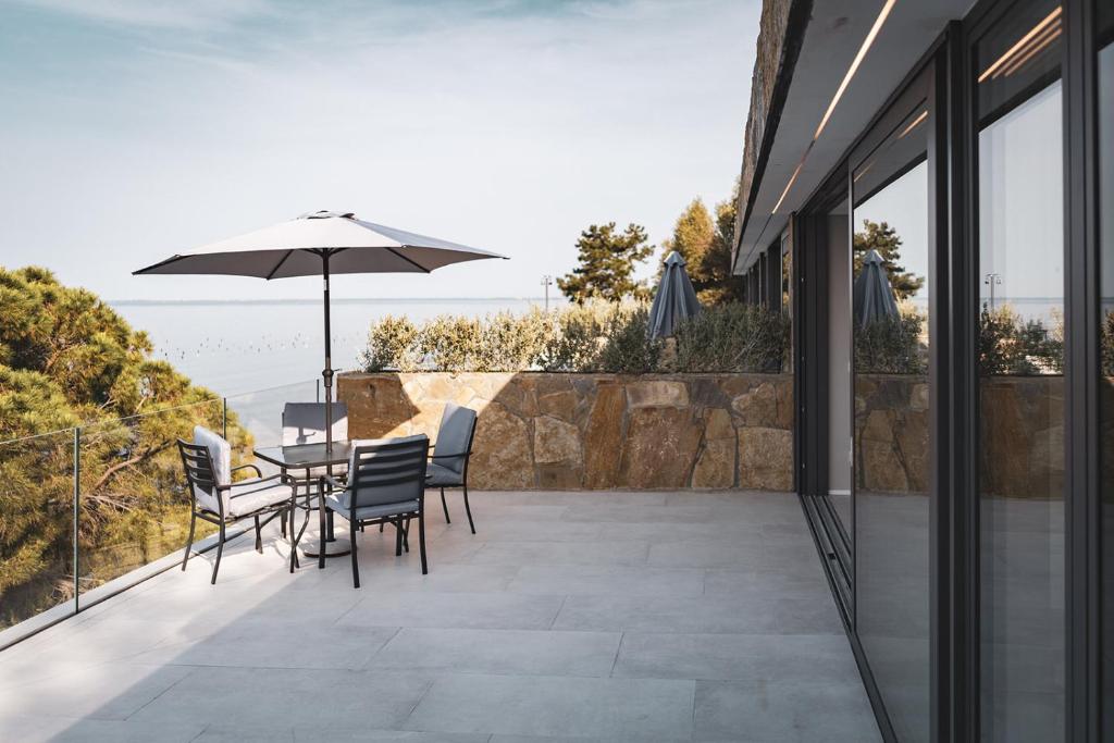 eine Terrasse mit einem Tisch, Stühlen und einem Sonnenschirm in der Unterkunft Seaside Resort in Triest