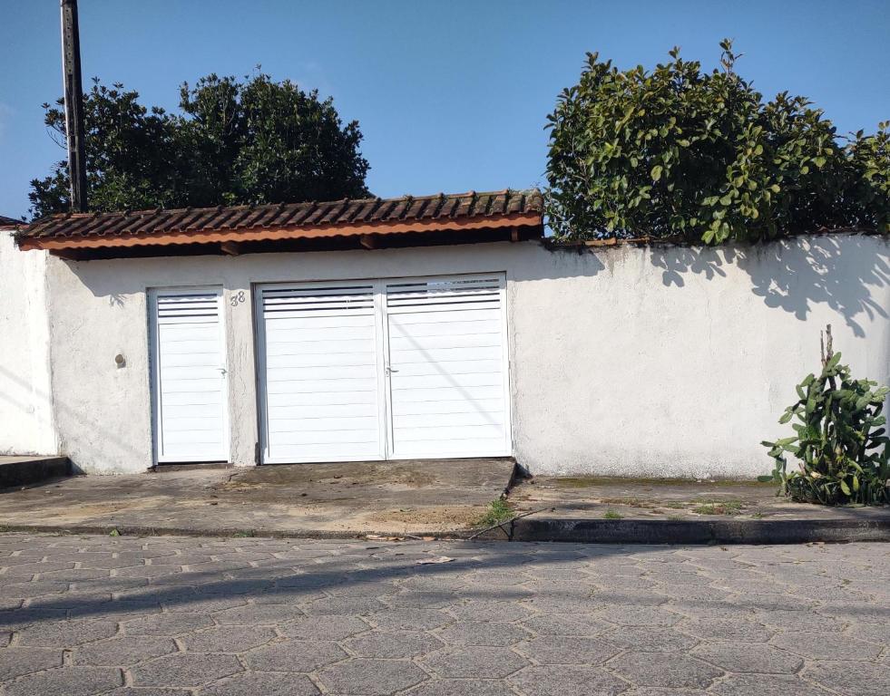 una casa bianca con due porte bianche in garage di Casa Praia Itanhaém a Itanhaém