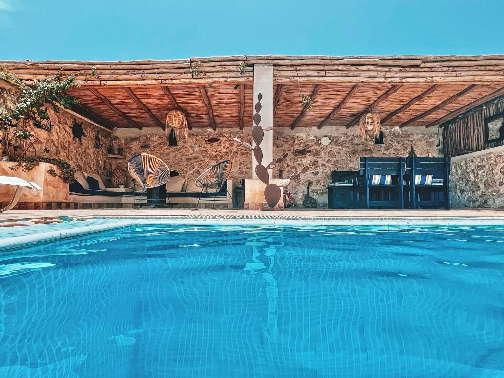 a swimming pool in front of a stone building at Dar Macha in Ghazoua