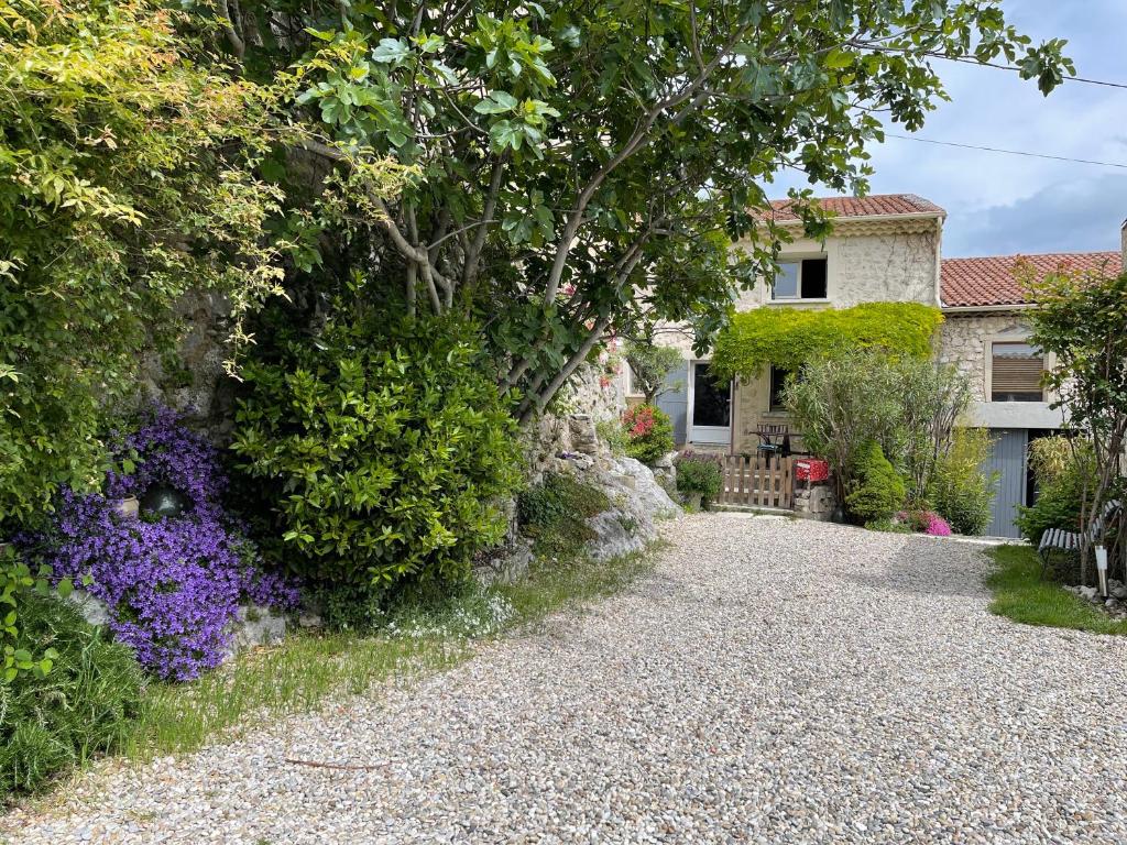 a house with a gravel driveway and flowers at La Bugadière in Salles-sous-Bois