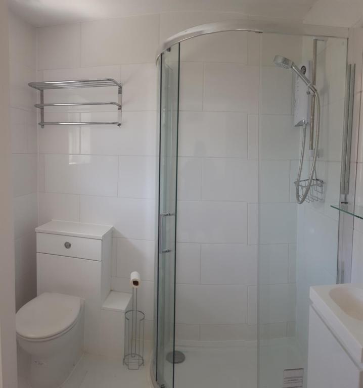 een witte badkamer met een douche en een toilet bij Bungalow by the sea in Hunstanton