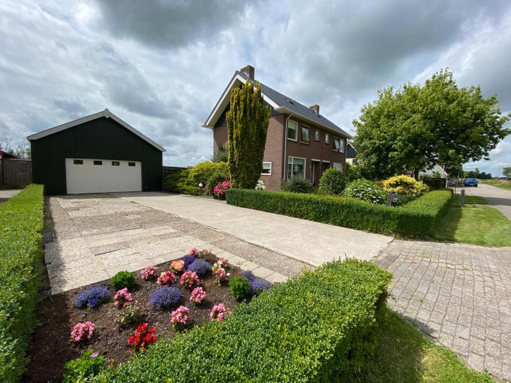 a house with a flower bed in front of a driveway at Woning aan het water in het Friese Merengebied in Jutrijp
