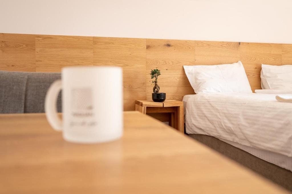 uma caneca de café sentada numa mesa ao lado de uma cama em Maglian Campus em Divčibare