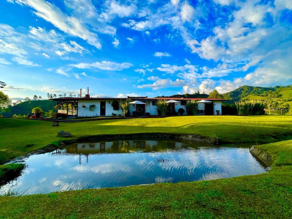 a golf course with a pond in front of a house at Cabanas La Herradura in Santa Rosa de Cabal