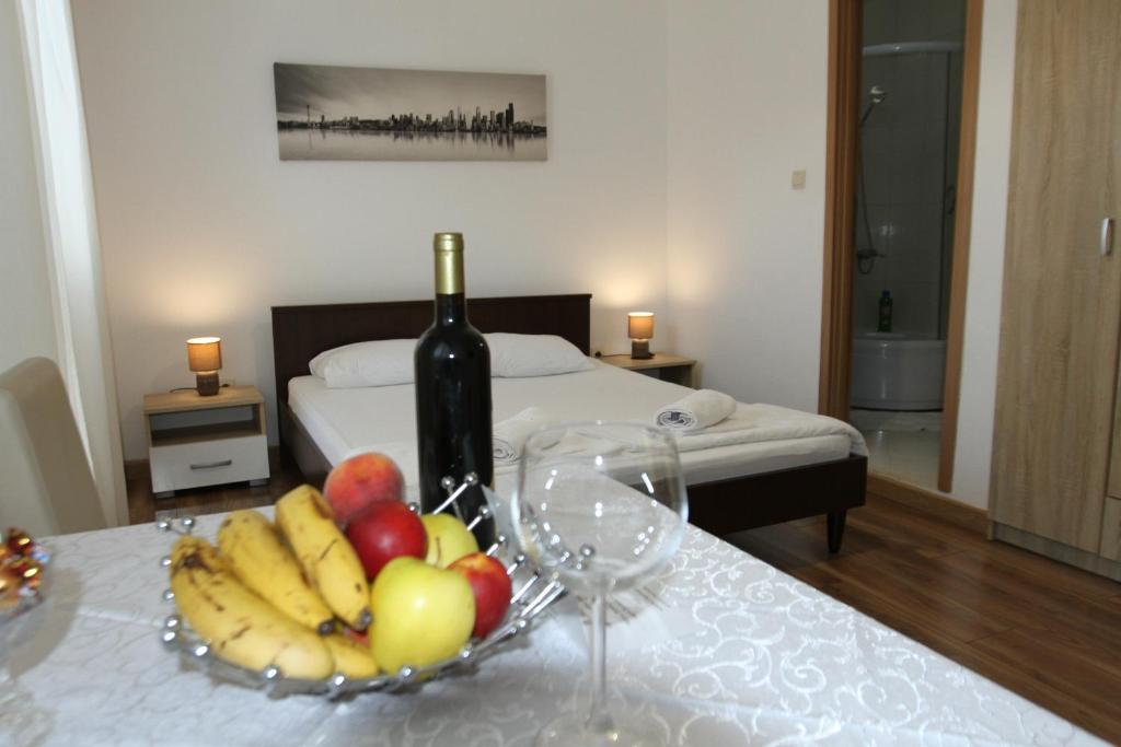 a bottle of wine and a bowl of fruit on a table at Apartments Muhar in Sveti Stefan