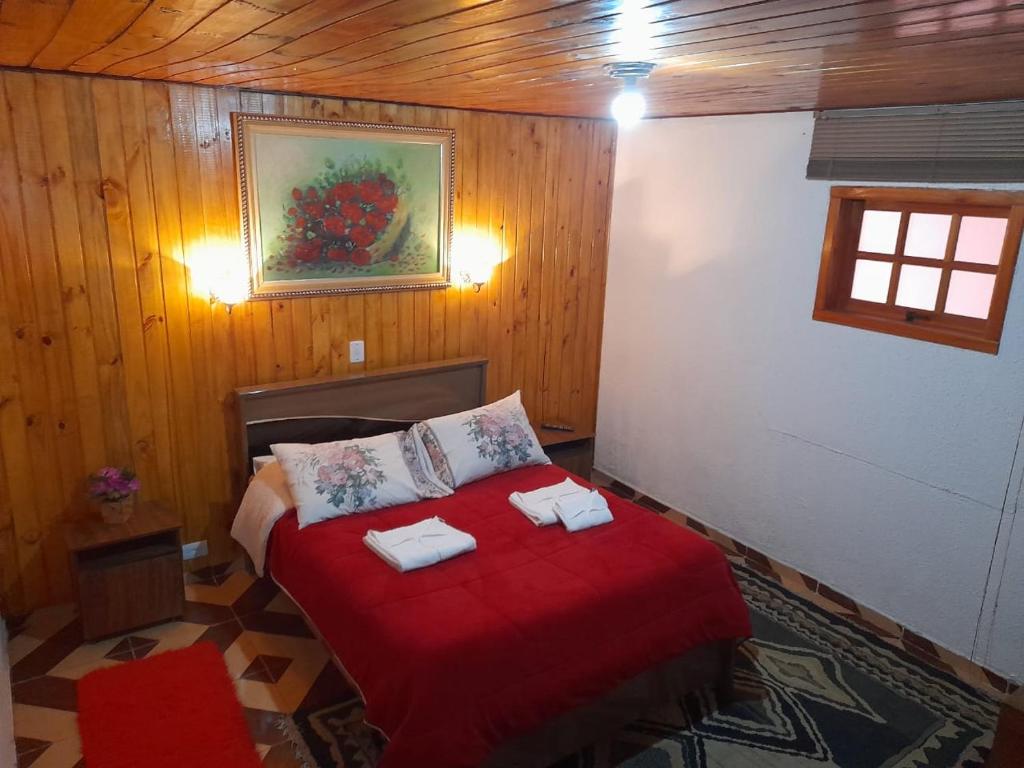 Un dormitorio con una cama roja con toallas. en Casa da Dine - Cama & Café, en Campos do Jordão