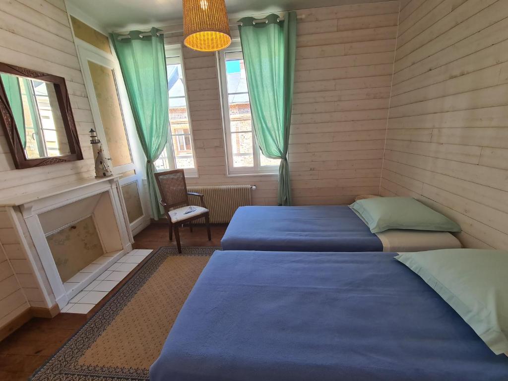 Duas camas num quarto com lareira e cortinas verdes em Maison de pêcheur typique proche plage em Fécamp