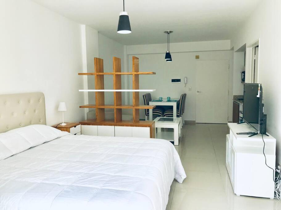 1 dormitorio con 1 cama blanca y TV en Departamento con pileta, parilla y gym en Recoleta - Piso 7 en Buenos Aires