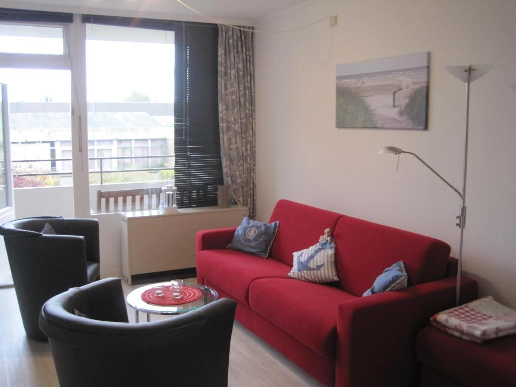 ein Wohnzimmer mit einem roten Sofa und einem Fenster in der Unterkunft Apartment Marina Wendtorf in Wendtorf